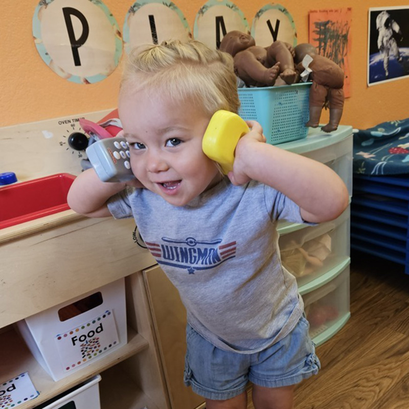 a little girl holding 2 phones